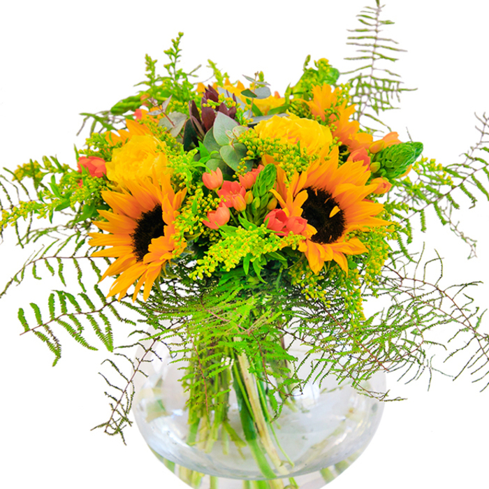 The instant you see this bouquet, you're met with a rush of sunlit exuberance-a spectacle reminiscent of bright afternoons in the heart of St Luke's. Blazing sunflowers with satiny, deep yellow petals burst forth, their faces turned outward as if gathering the last rays from nearby parks. Beside them, layers of golden garden roses unfold delicately, their rich spirals glowing with a gentle warmth. Scattered among the blooms, glossy red hypericum berries sparkle in small clusters, a playful counterpoint among layers of lush green foliage. Feather-light ferns and airy sprigs of goldenrod fill out the design, their intricate textures and slender spikes imbuing a rhythmic natural movement. Subtle strains of blue-green eucalyptus weave through the display, offering a cooling touch and a reminder of wild, unmanicured beauty. The arrangement is anchored in a clear, rounded glass vase-resembling a miniature fishbowl-that reveals the vivid stems reaching into fresh water below. The bouquet exudes a sense of festive joy and is equally fitting for birthday tables, anniversary dinners, or as a welcoming sight at the entryway of a local St Luke's townhouse. Each element is chosen for freshness and vibrancy, evoking the lingering scents of a late summer garden and the serenity of well-loved neighbourhood green spaces.