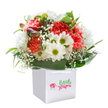 With its joyful array of coral, peach, and red carnations, backed by gleaming white daisies and airy sprigs of baby's breath, this bouquet feels like a vivid slice of St Luke's in bloom. Every carnation's petal is touched by a warm softness, each flouncy and full, while the daisies' bright yellow-green centers add playful bursts of happiness reminiscent of the lively greens in Fortune Street Park. Dotted throughout, delicate clouds of gypsophila lend an innocence and lightness, their tiny blossoms shimmering in the gentle daylight that fills the scene. Framing the flowers, lush deep green leaves create a natural cradle, reminiscent of the foliage you'd find just off Bath Street, providing texture and substance. Tucked on the left, a few buds with a hint of deep purple promise soon-to-be blooms and a moment of surprise. The entire arrangement is thoughtfully nestled inside a pristine white gift bag with elegant ribbon handles, ready to be delivered to a new home or offered as a spontaneous gesture to someone special in St Luke's. Perfect for birthday celebrations, congratulatory moments, or simply to bring a burst of colour and cheer, this bouquet conveys a sincerity and freshness that reflects the joyful spirit of the neighbourhood's finest florists. The clean, white backdrop focuses attention entirely on the flowers, making their beauty and craftsmanship shine in every detail.
